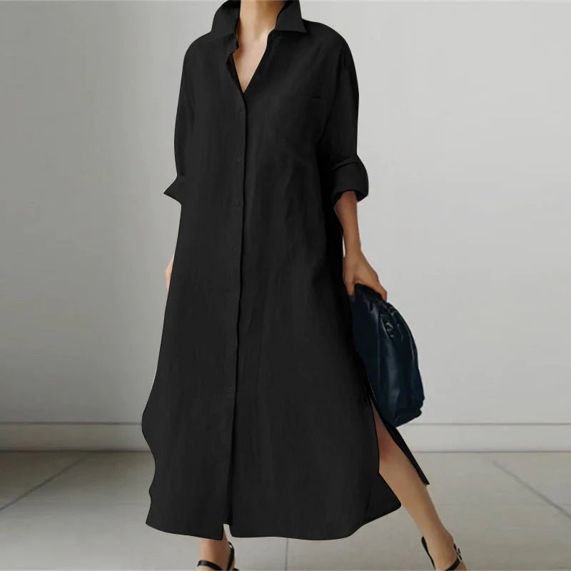 Woman wearing black oversized cotton shirt dress with collared neckline and button-through front, styled with handbag