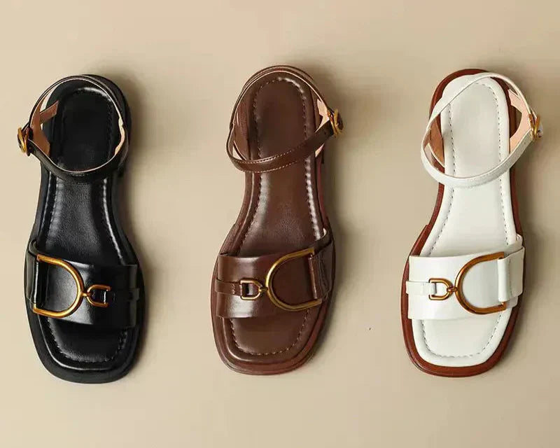 Close-up of adjustable gold buckle ankle strap on women's flat leather sandals in black finish