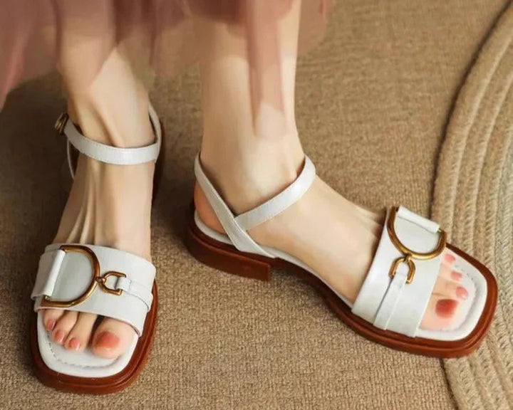 Women's black leather sandals with square toe design and gold-tone hardware on neutral background