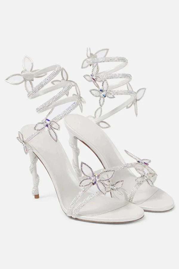 Close-up of butterfly embellishments and metallic straps on women's heeled sandals