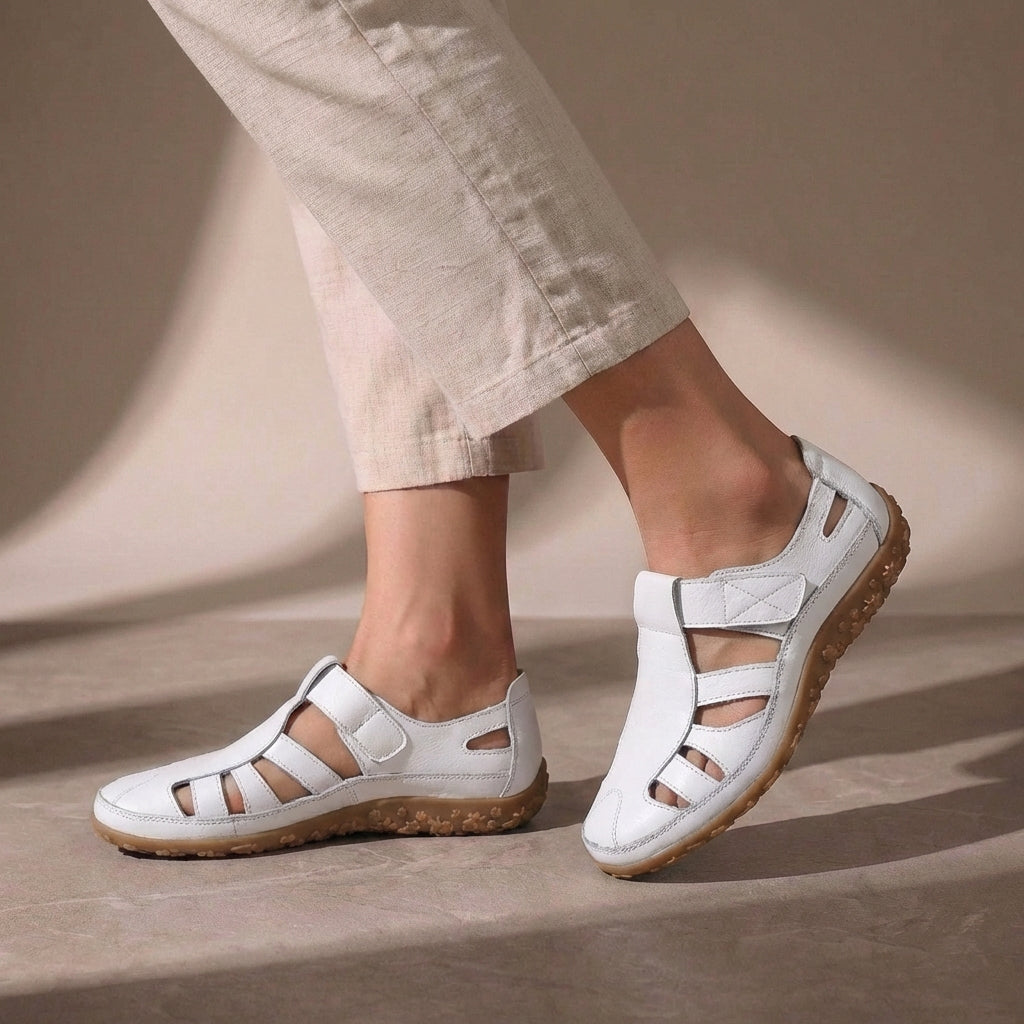 Charlotte wearing white Women's Orthopedic Adjustable Strap Closed Toe Sandals with beige trousers and textured sole visible
