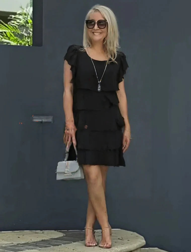 Tiered midi dress styled for daytime event with minimal accessories and natural lighting