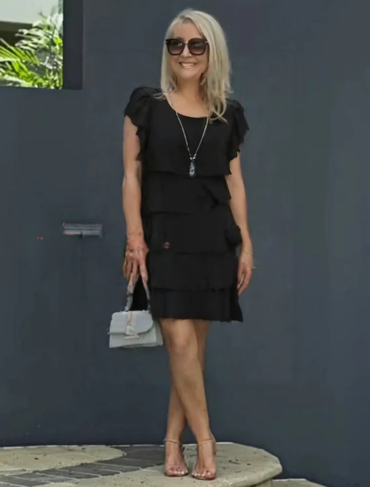 Tiered midi dress styled for daytime event with minimal accessories and natural lighting