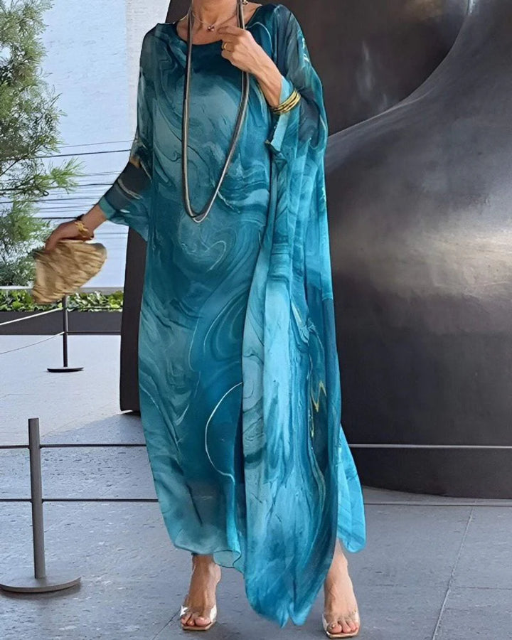 Woman wearing teal marble print maxi dress with batwing sleeves and relaxed flowing silhouette