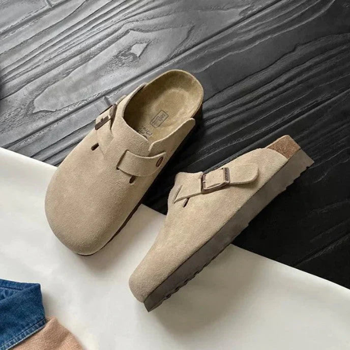 Women's clog sandals in beige suede with adjustable side buckle detail and closed-toe slip-on design for everyday wear