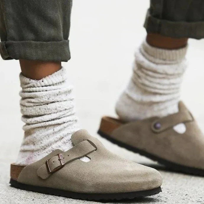 Close-up view of women's suede clog sandals showing buckle fastening and structured footbed for comfortable all-day support