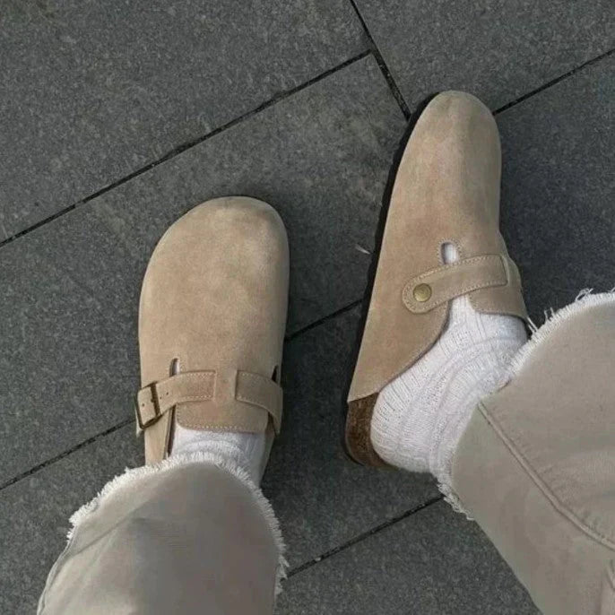 Beige suede clog sandals styled with casual denim, featuring closed-toe design and adjustable buckle for a tailored fit