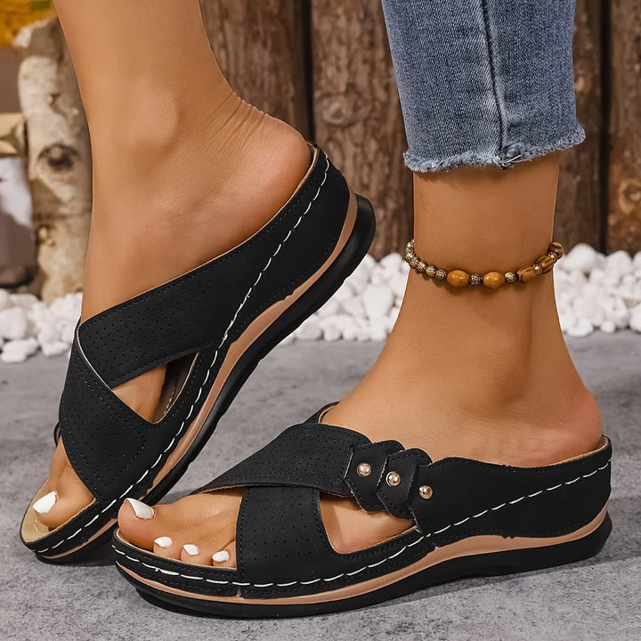 Women's navy wedge sandals on grey surface showing anti-slip sole and buckle detail