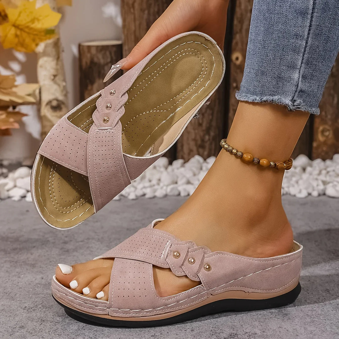 Women's navy wedge sandals styled with casual summer outfit on textured surface
