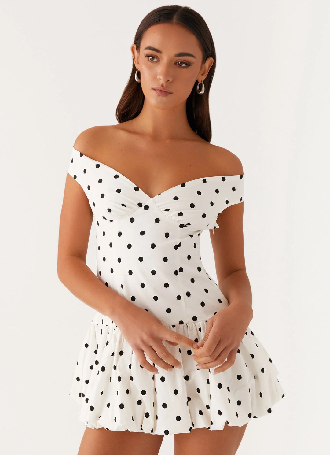 Harriet wears the Off-Shoulder Polka Dot Peplum Mini Dress featuring an off-the-shoulder neckline and high-waist peplum silhouette with scattered polka dots