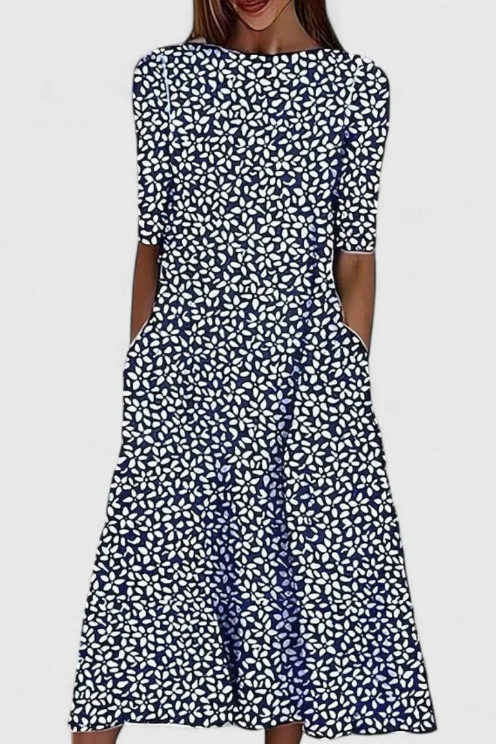 Close-up detail of blue leaf pattern on white midi dress fabric with round neckline