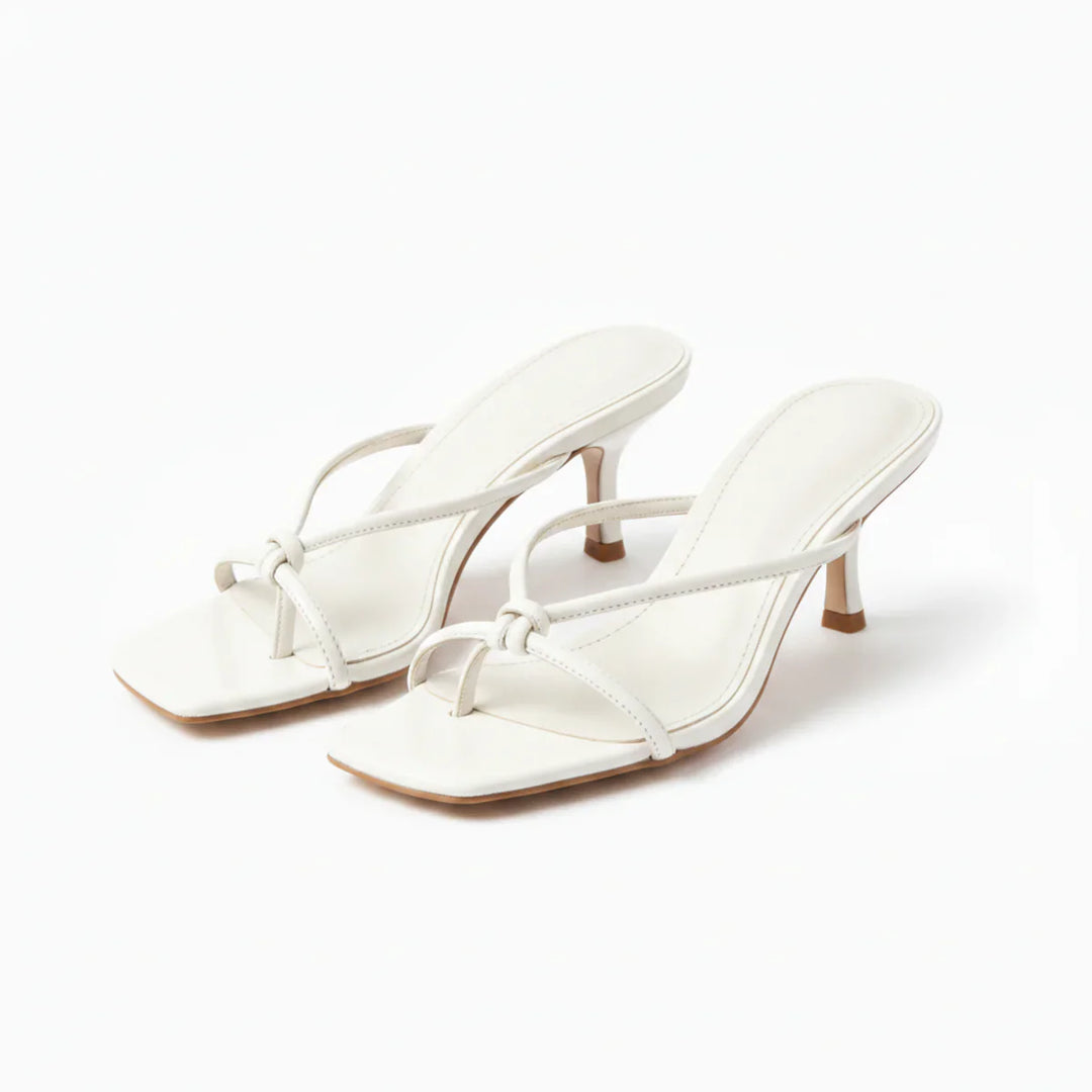 Close-up of women's heeled sandals showing knot strap and flared mid-height heel construction