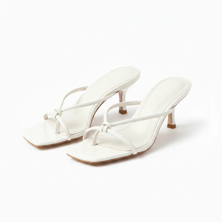 Close-up of women's heeled sandals showing knot strap and flared mid-height heel construction