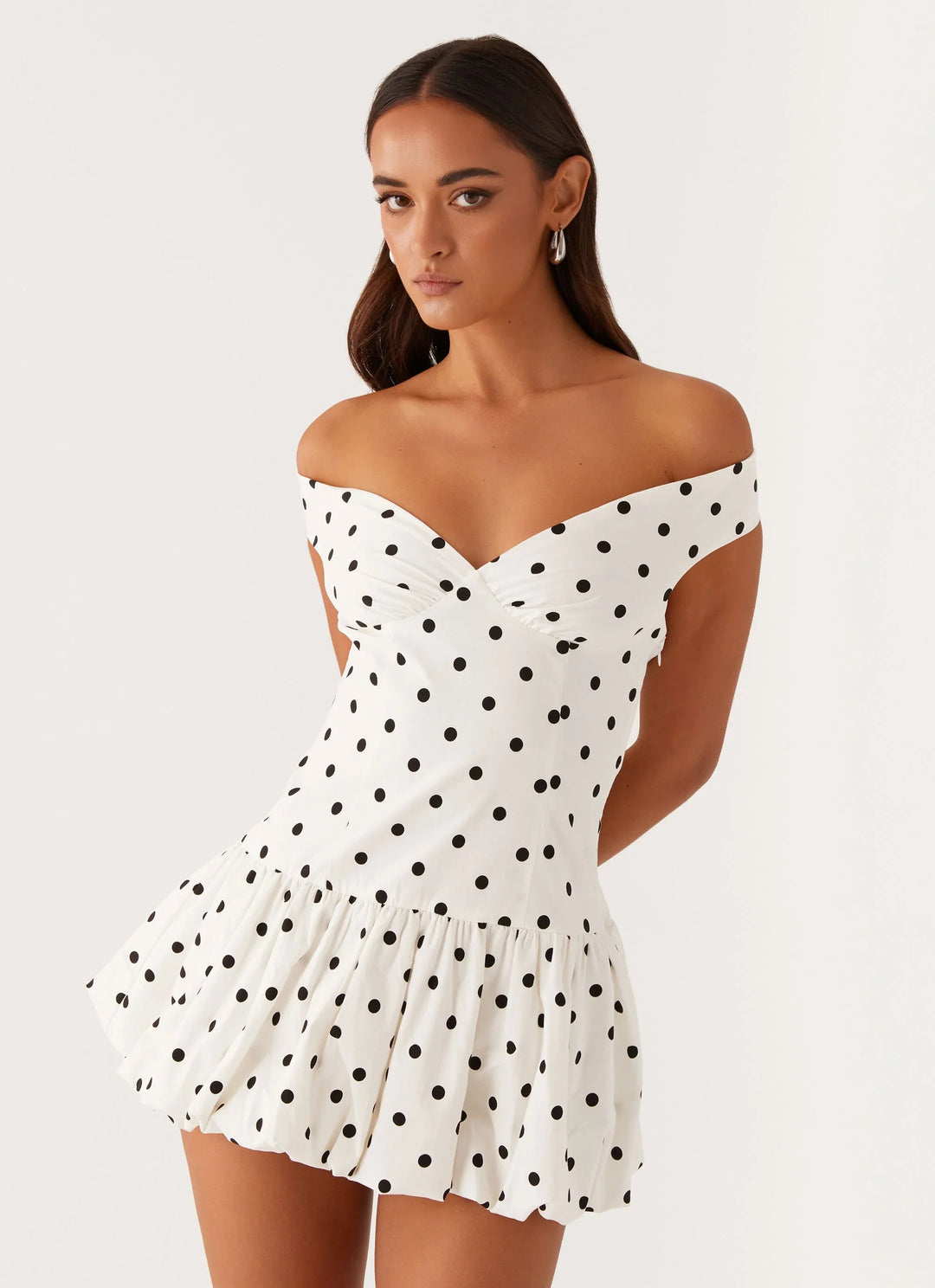 Close-up view of off-shoulder polka dot peplum mini dress showing fitted bodice and playful polka dot print detail
