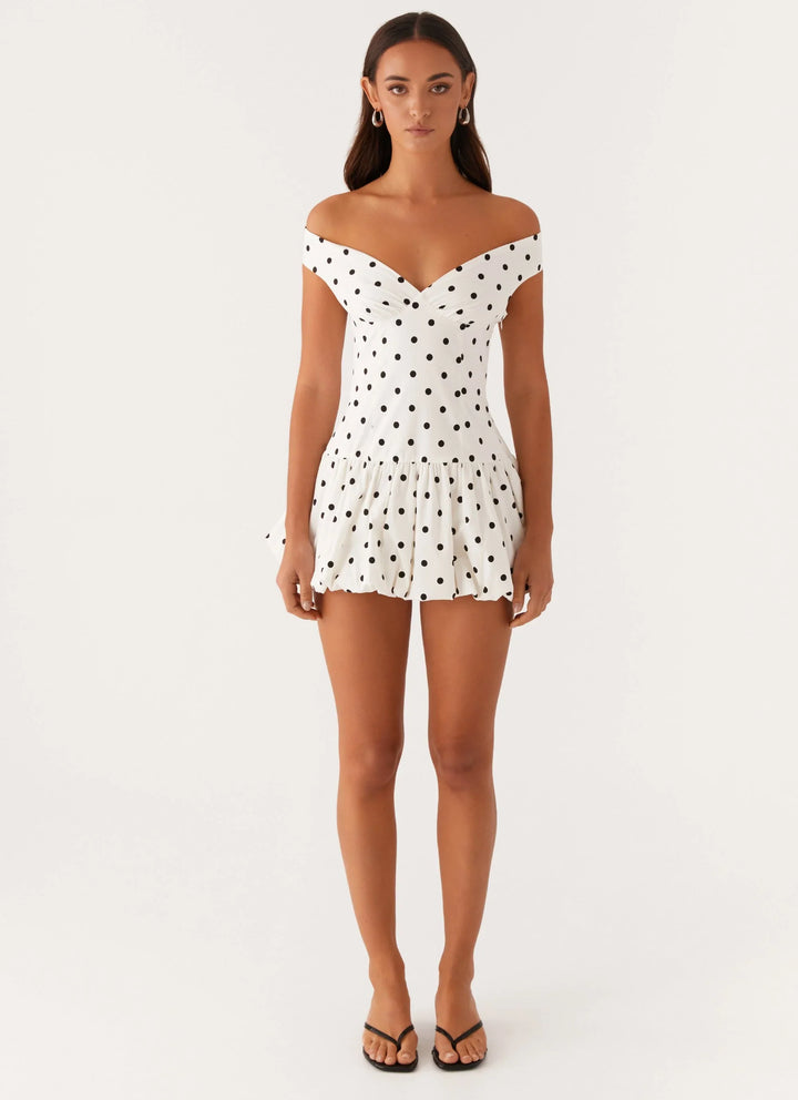 Full-length view of off-shoulder polka dot peplum mini dress showing the flared skirt and flattering feminine silhouette