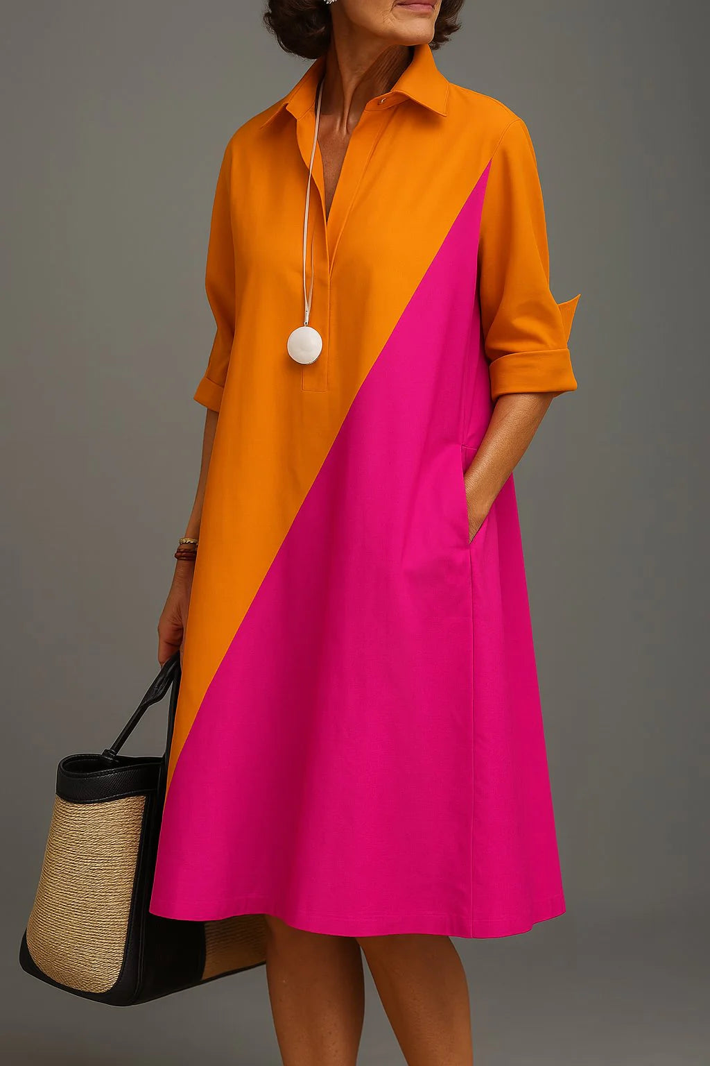 Woman wearing diagonal colourblock midi dress with orange and fuchsia panels, classic collar, and roll-tab sleeves