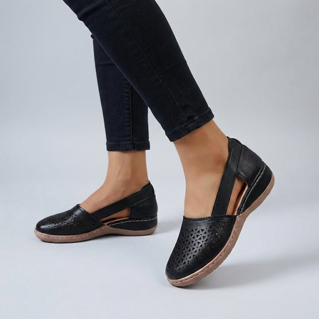 Mabel wearing Women's Orthopedic Scalloped Cut-Out Comfort Sandals in black with decorative perforations and back strap