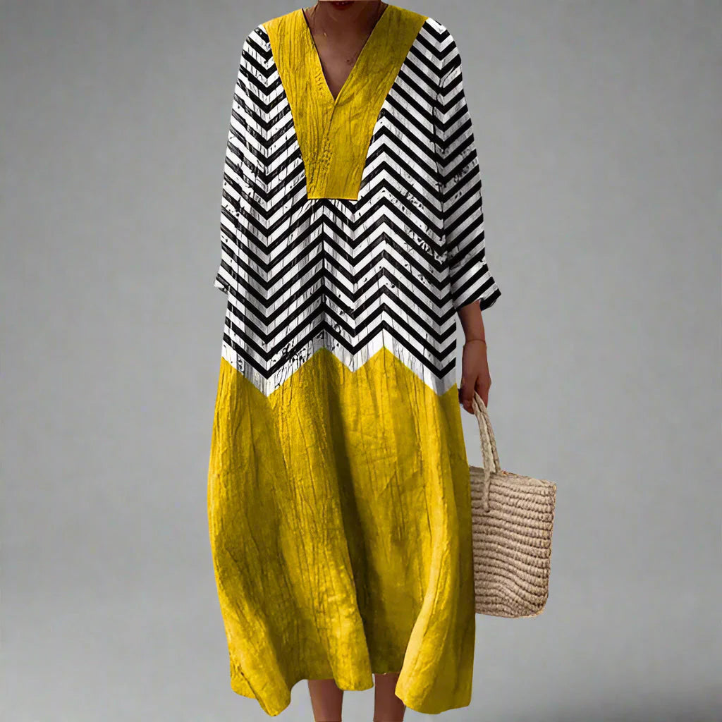 Elegant summer dress with bold chevron print bodice and vibrant yellow colour-blocked skirt, featuring V-neckline and three-quarter sleeves