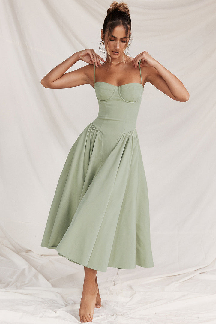 Matilda wearing a sage green corset midi dress with adjustable straps and gathered skirt