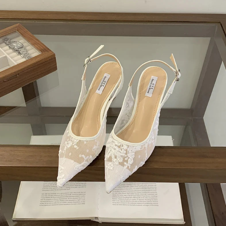 Women's white lace slingback heels with pointed toe and beaded embroidery detail on display