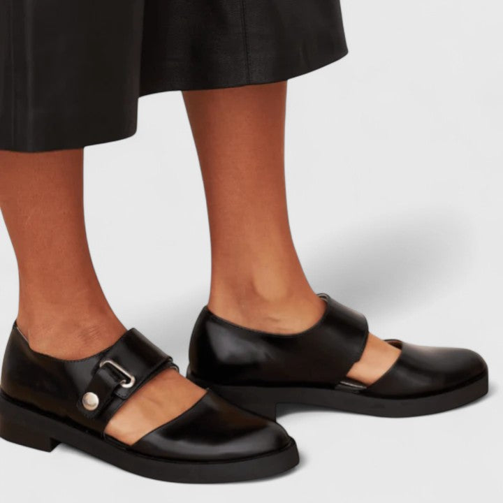 Women's orthopedic buckle shoes in black with adjustable strap and structured low-profile silhouette for everyday comfort