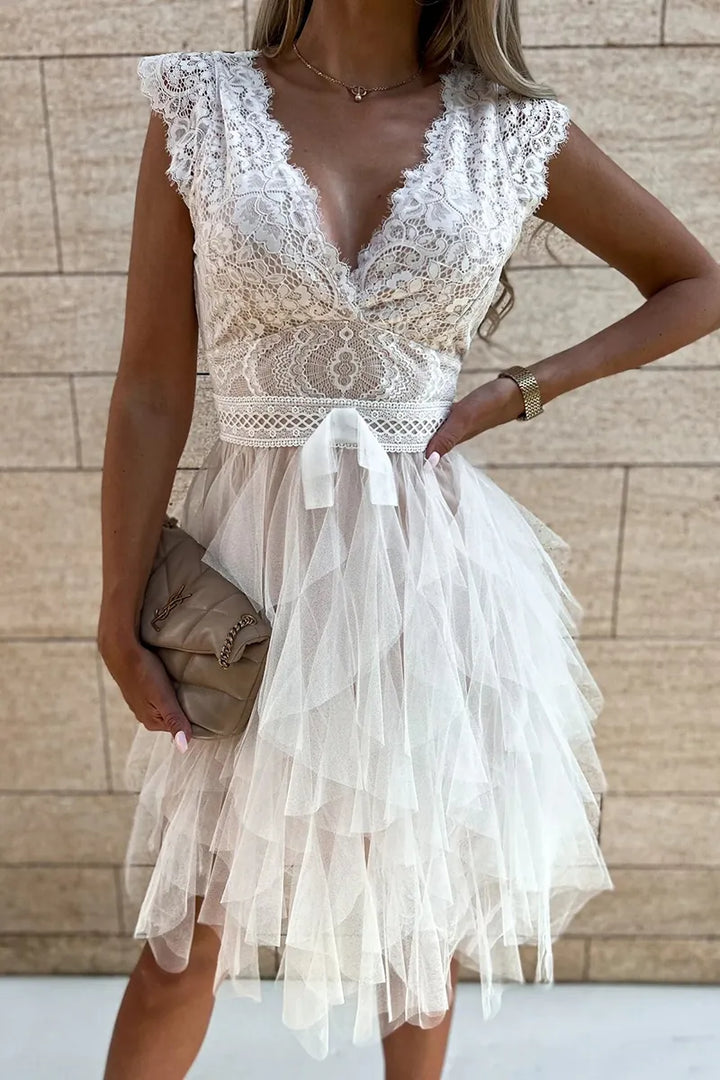 Close-up view of ruched bodice and flared ruffle hem detail on white cocktail mini dress