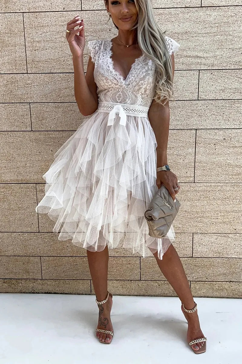 Full-length view of sleeveless white mini dress with structured bodice and flowing ruffle hem