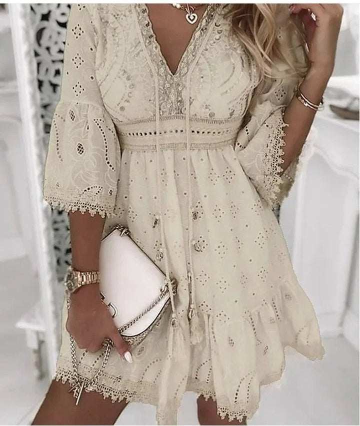 Side angle showing flowing bell sleeves and A-line shape of boho mini dress in cream lace