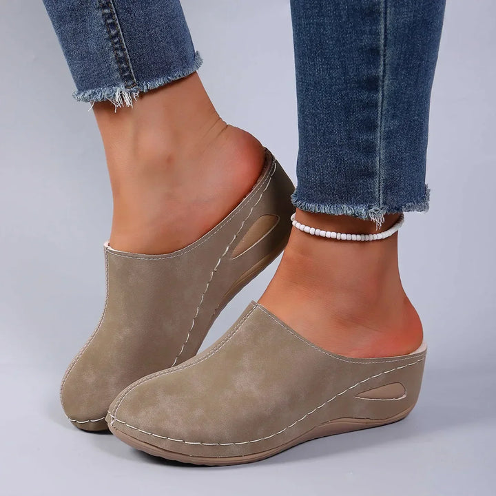 Side profile of women's slip-on slippers with cushioned footbed and open-back design for easy wear