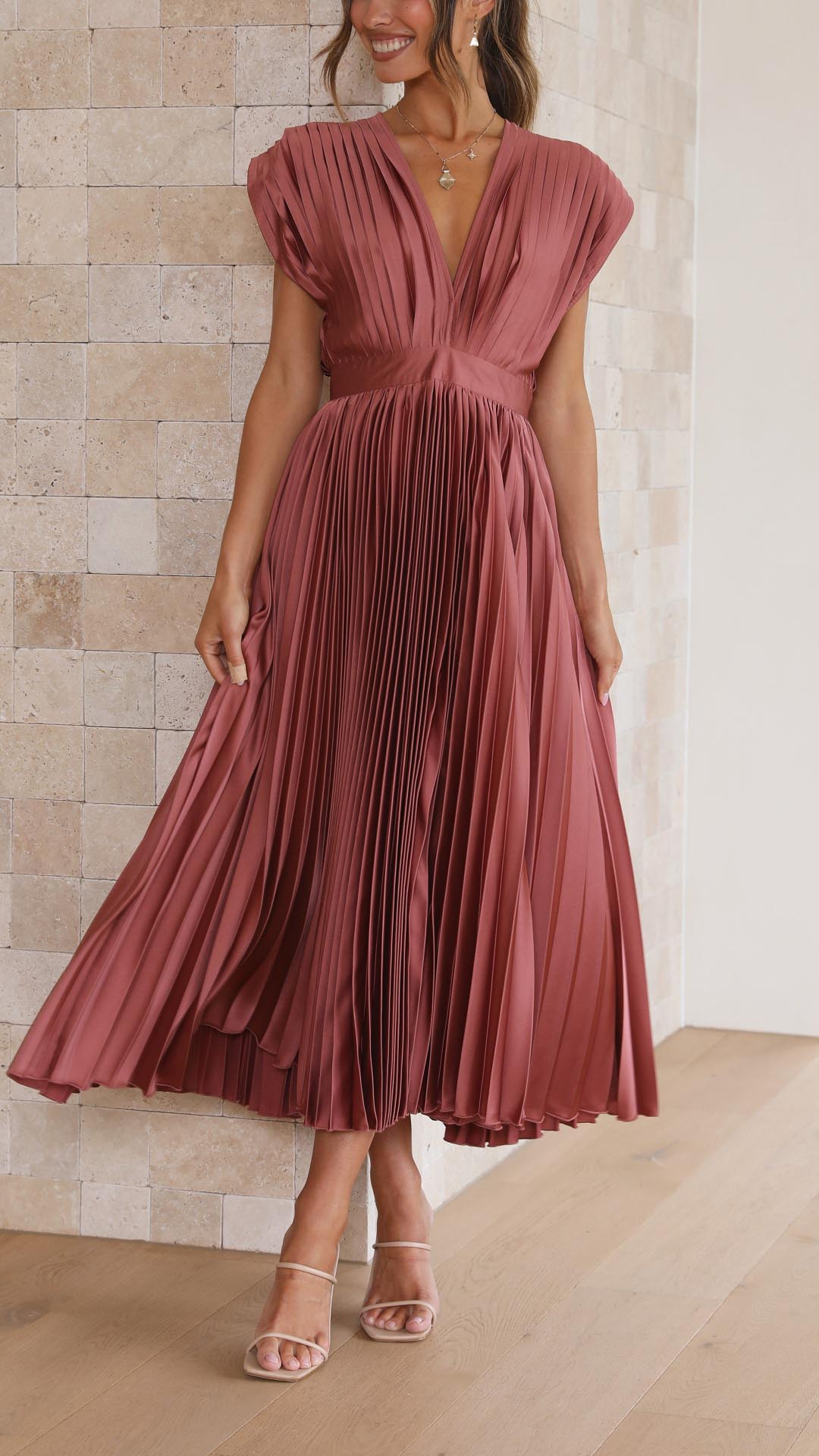 Front view of pleated midi wedding guest dress showing deep V-neckline and vertical pleating detail