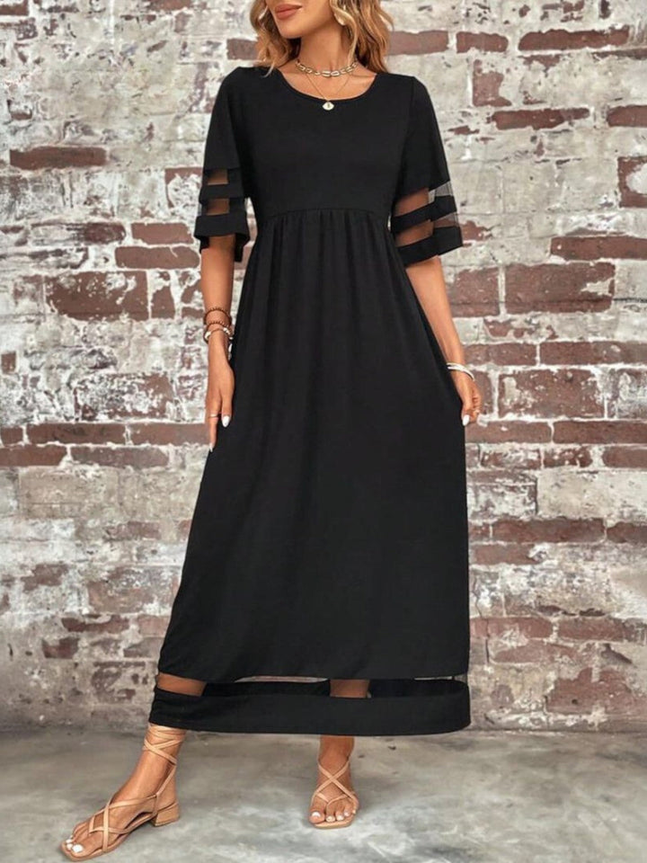 Back view showing the flowing drape and mesh trim detail at the hem
