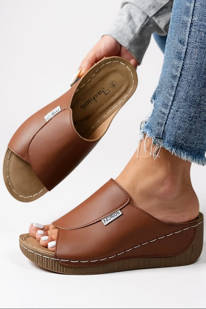 Woman wearing cream platform slides with denim shorts and grey jumper