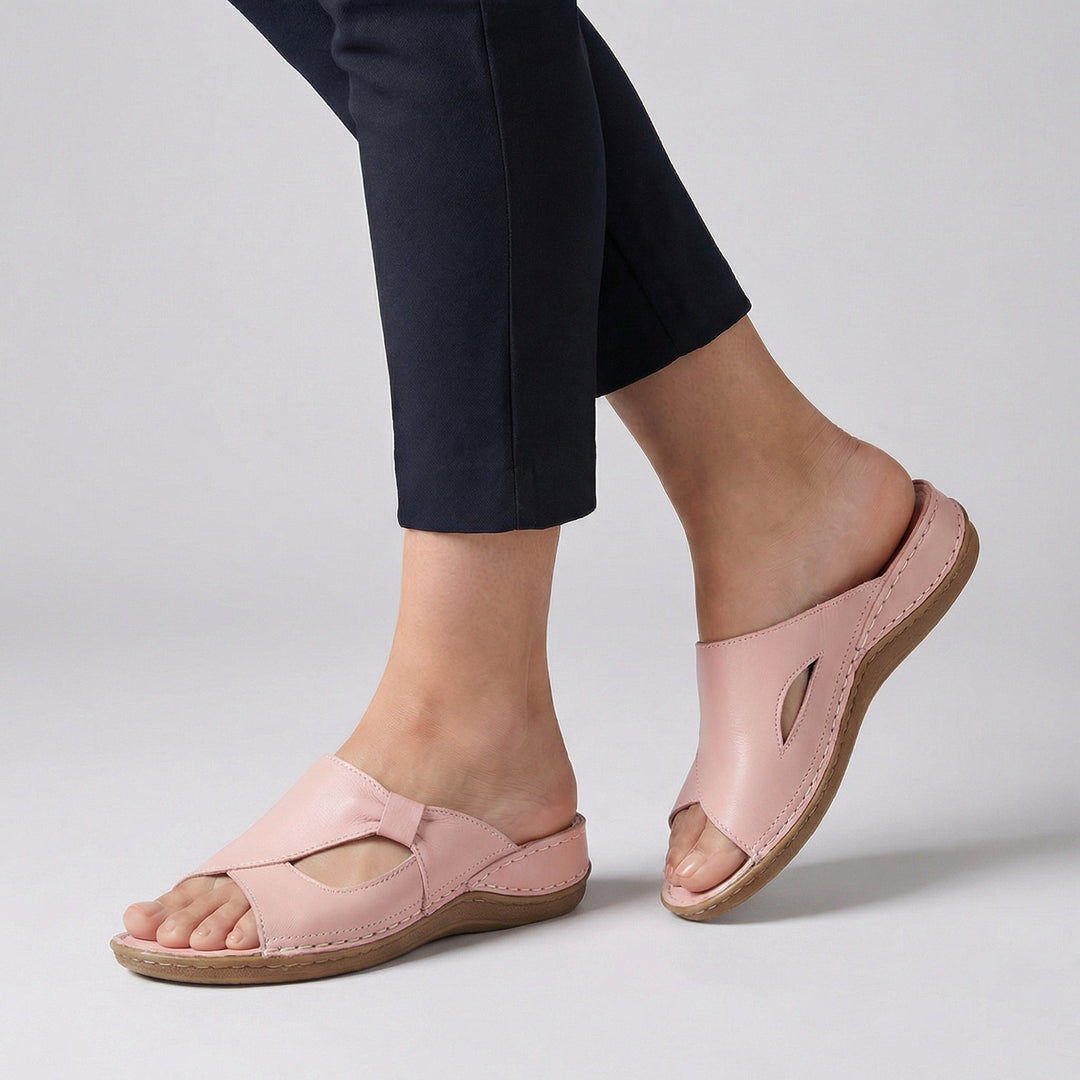 Side profile of slip-on sandals showing leather-effect upper with decorative stitching and wedge heel
