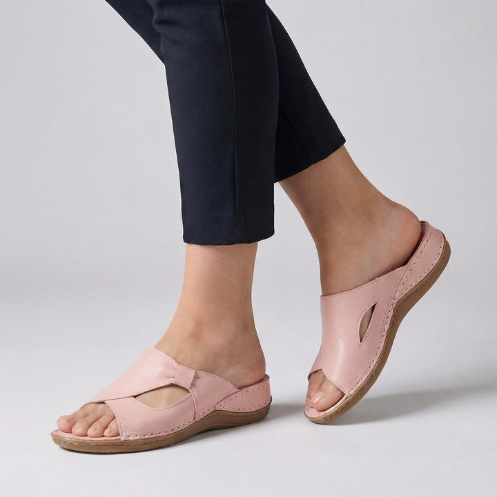 Side profile of slip-on sandals showing leather-effect upper with decorative stitching and wedge heel