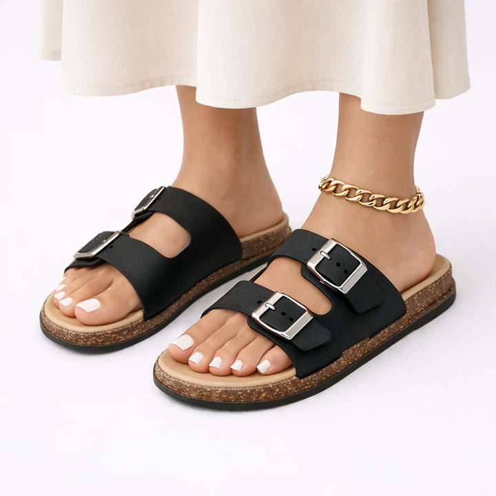 Side view of tan slip-on sandals with wide double straps and cork-effect flat sole
