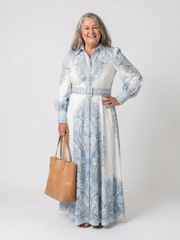 Side angle of belted waist and flowing maxi-length skirt on high neck printed dress